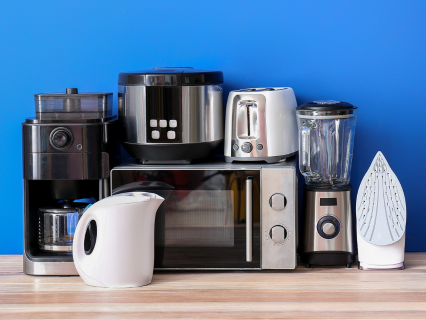 Elektrokleingeräte Verschiedene Elektrokleingeräte auf der Holztheke auf blauem Hintergrund. Kaffeemaschine, Mikrowelle, Wasserkocher, Nudelmaschine, Toaster, Standmixer & Bügeleisen