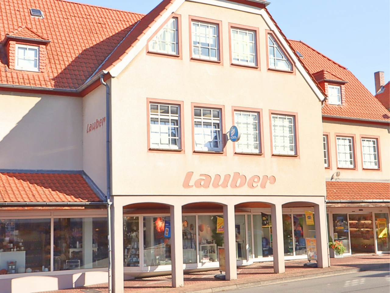 Frontansicht vom Kaufhaus Lauber Frontales Bild vom Kaufhaus Lauber. Kaufhausgebäube von außen mit dazugehöriger Fußgängerpassage. Große Schaufenster mit einem Bild in die Haushaltswarenabteilung. Große Logoaufbringung "Lauber" auf dem Geschäftsgebäude.