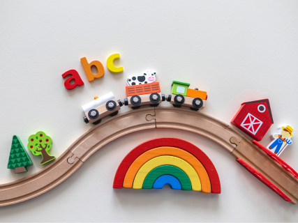 Spielwaren Sortiment Hölzerne Spielzeugeisenbahnstrecke mit verschiedenen bunten Holzbausteinelementen und einer Eisenbahn. Bäume und Häuser, sowie ein "abc" Schriftzug aus den hölzernen Spielelelementen